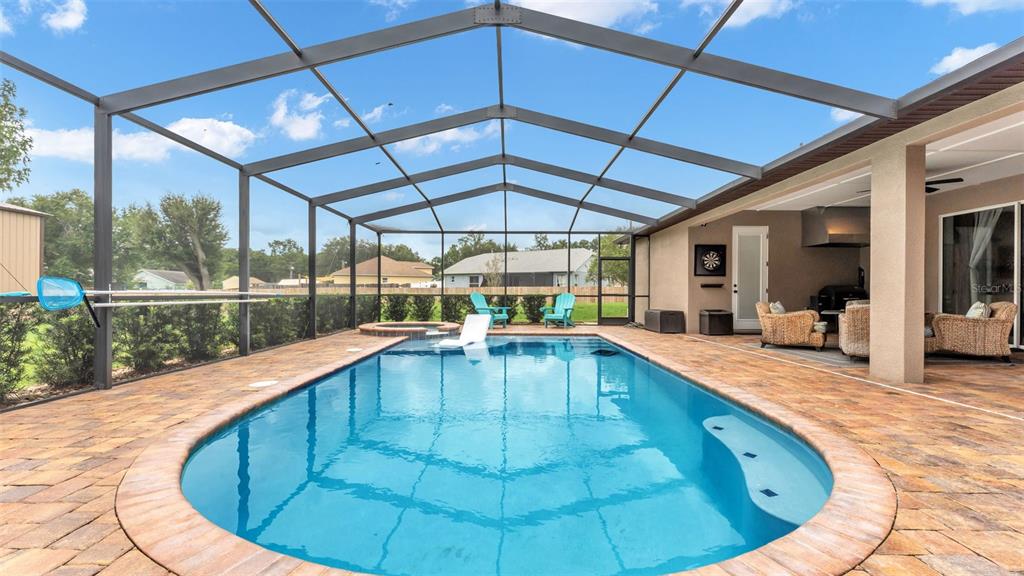 A rectangular swimming pool with a spa sits inside a screened-in patio with pavers — 3430 N GALLOWAY ROAD, LAKELAND, FL