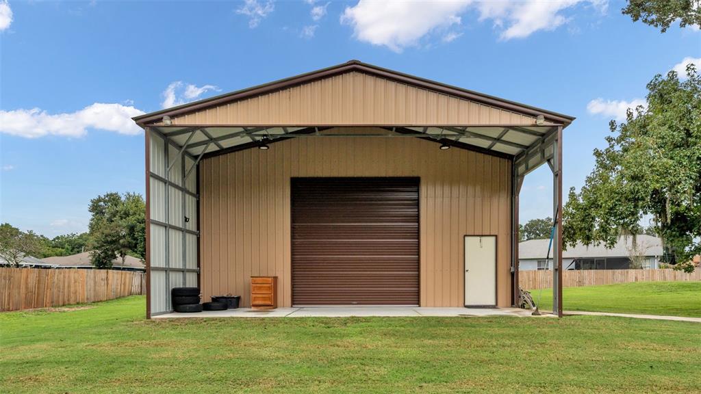 A tan metal workshop building with a large roll-up door and a side entry door — 3430 N GALLOWAY ROAD, LAKELAND, FL