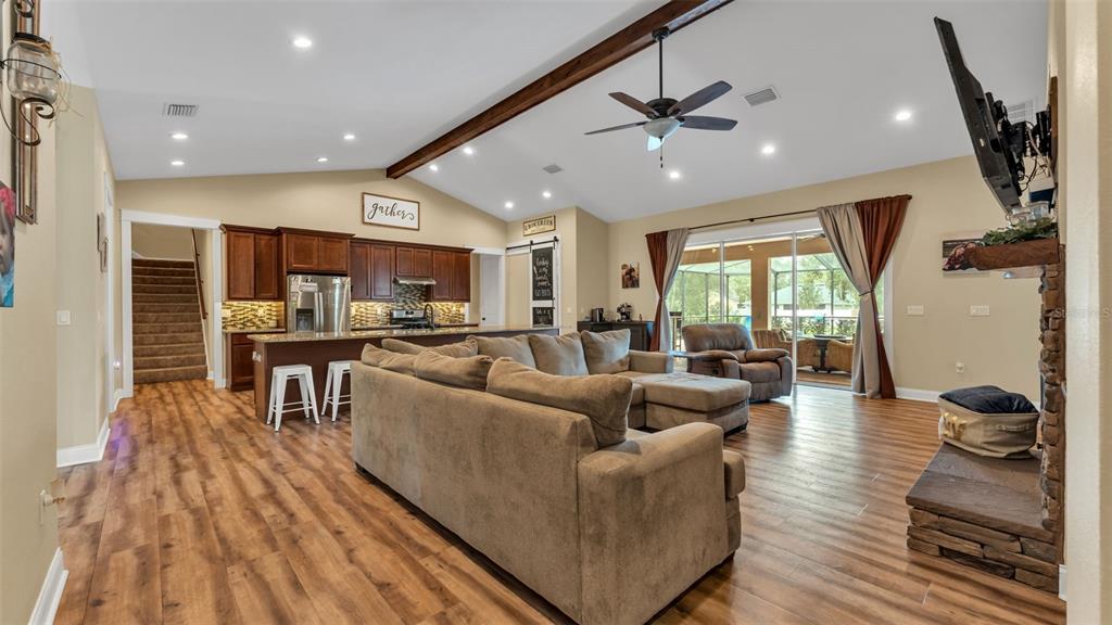 A living room with wood-look flooring, a large sectional sofa, and an open kitchen — 3430 N GALLOWAY ROAD, LAKELAND, FL