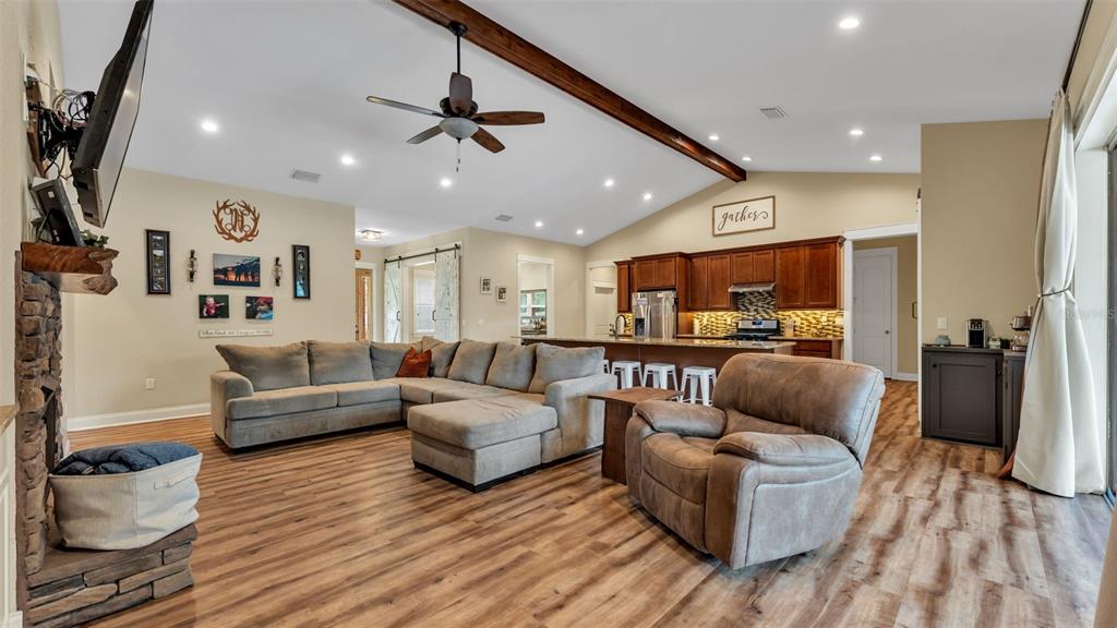 An open-concept living room and kitchen featuring wood-look flooring, a sectional sofa, and vaulted ceilings — 3430 N GALLOWAY ROAD, LAKELAND, FL