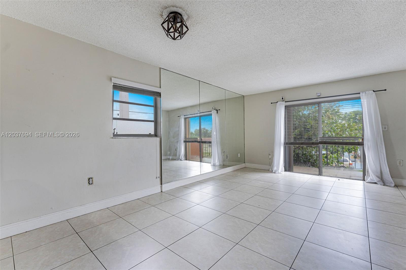 A room with tiled floors, a mirrored wall, a window, and sliding glass doors — 1100 W 35th St # 23, Hialeah FL 33012, HIALEAH, FL