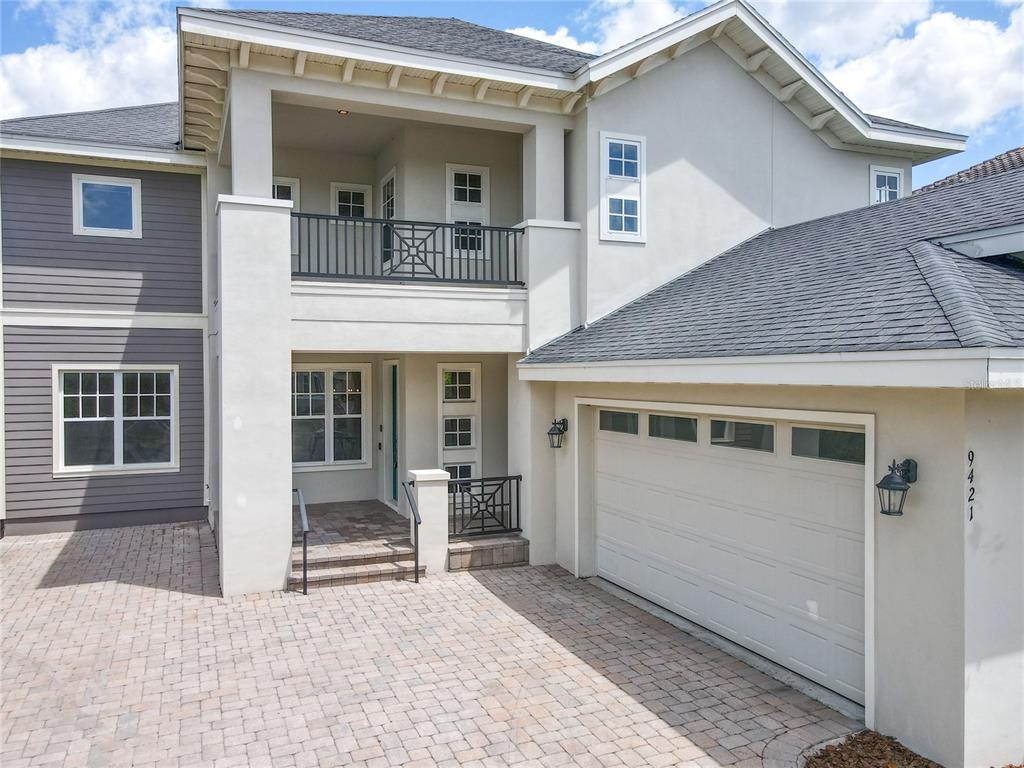 A two-story house exterior features a paved driveway, a garage, and an upper-level balcony — 9421 DUGARD COURT, ORLANDO, FL