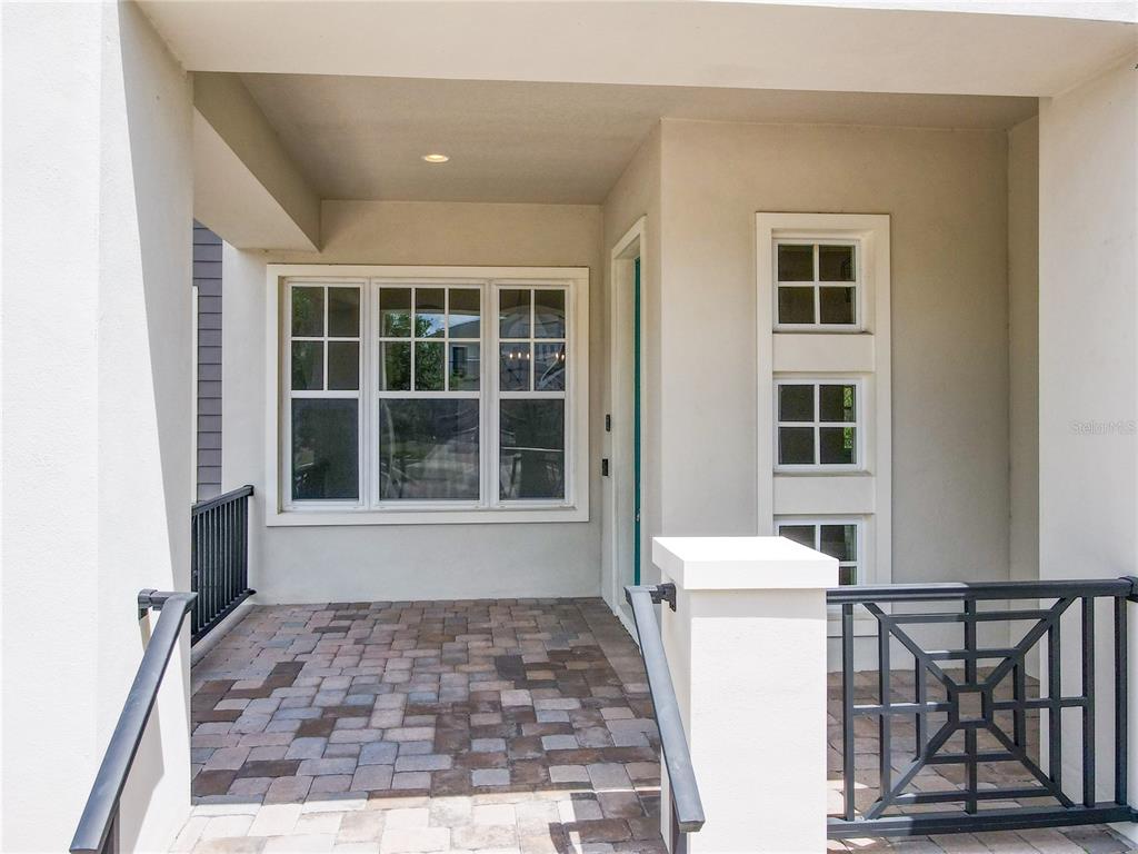 A paved front porch features a large window, a teal door, and black metal railings — 9421 DUGARD COURT, ORLANDO, FL