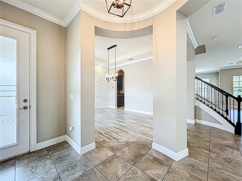 A foyer with tile flooring leads through an arched entryway into a dining area — 9421 DUGARD COURT, ORLANDO, FL