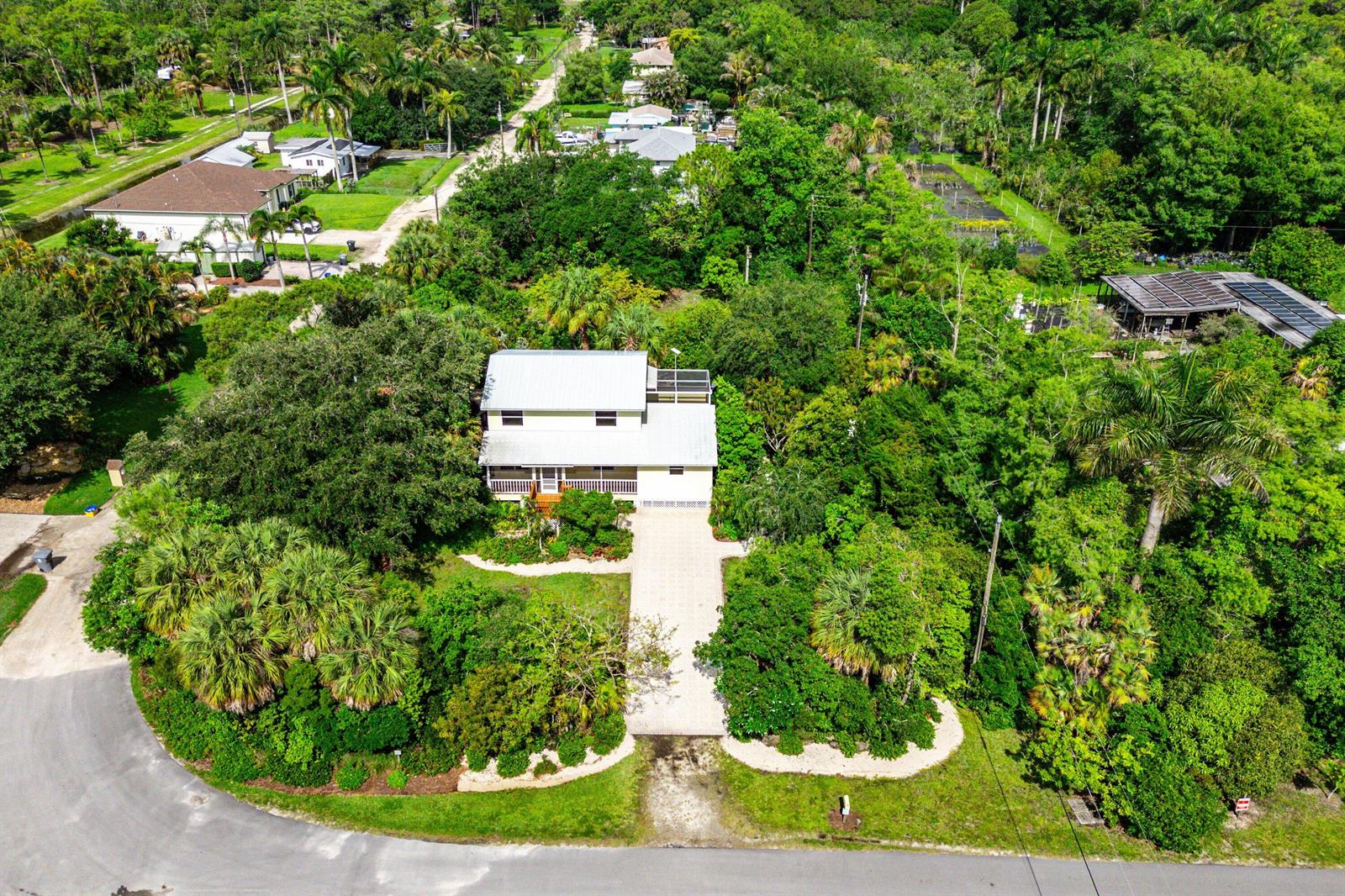 An aerial view shows a two-story house with a metal roof surrounded by dense trees — 7713 Park Lane Road, Lake Worth FL 33449, LAKE WORTH, FL