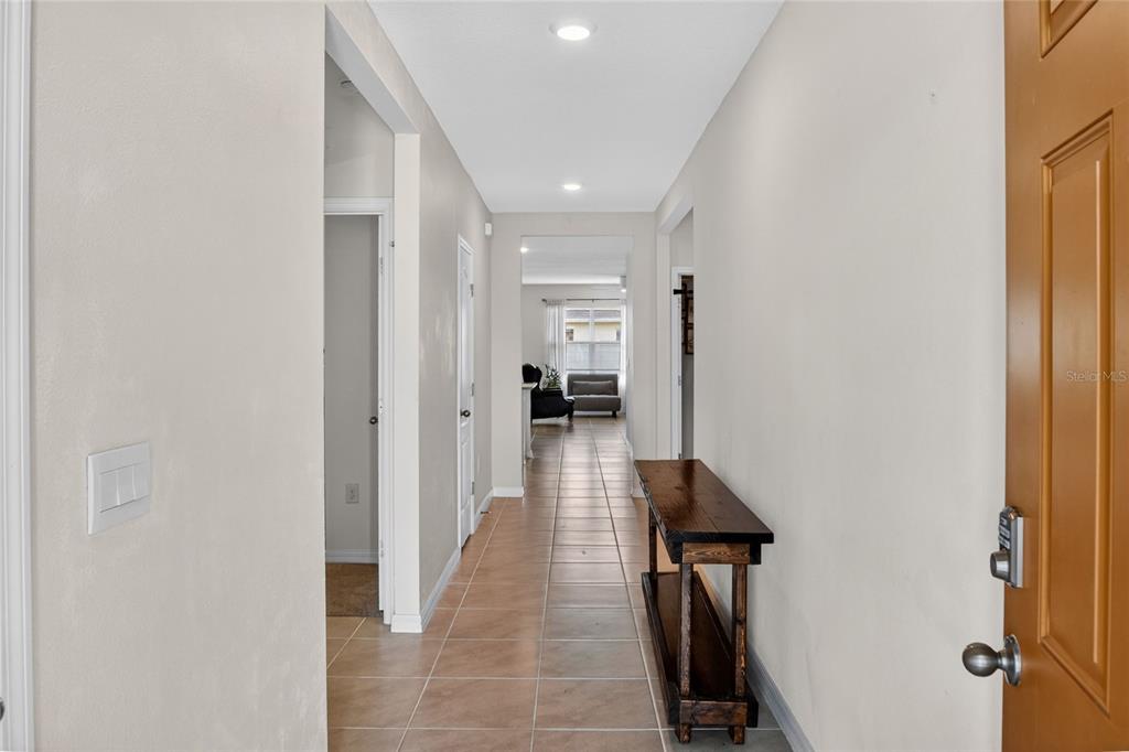 A tiled entryway leads down a hallway toward a living area with a wooden console — 4981 FOXGLOVE CIRCLE, LAKELAND, FL