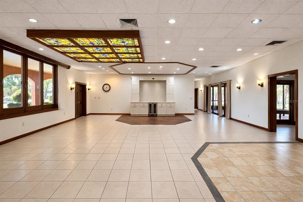 A spacious room features light tile flooring, a stained-glass ceiling panel, and a built-in bar — 6 PALM WAY, HAINES CITY, FL