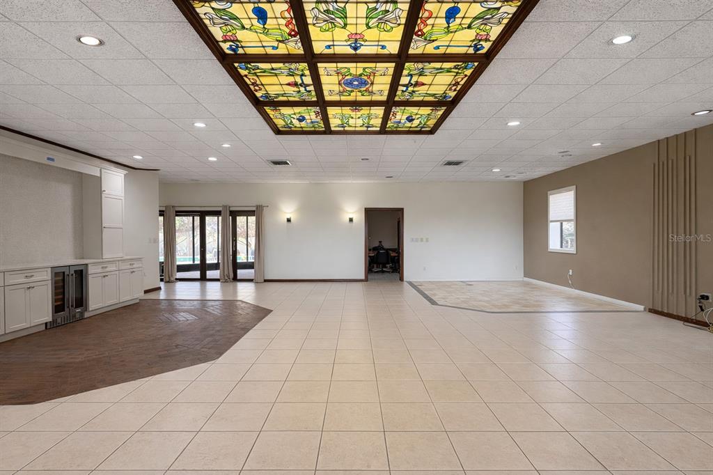 A large room features a stained-glass ceiling panel, tile flooring, and a built-in wet bar — 6 PALM WAY, HAINES CITY, FL