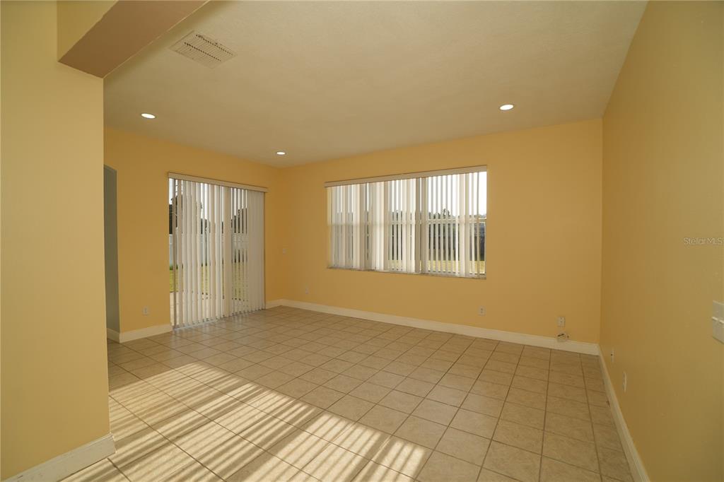 An empty room with light-colored tile flooring, yellow walls, and vertical window blinds — 2560 SAGE DRIVE W, KISSIMMEE, FL