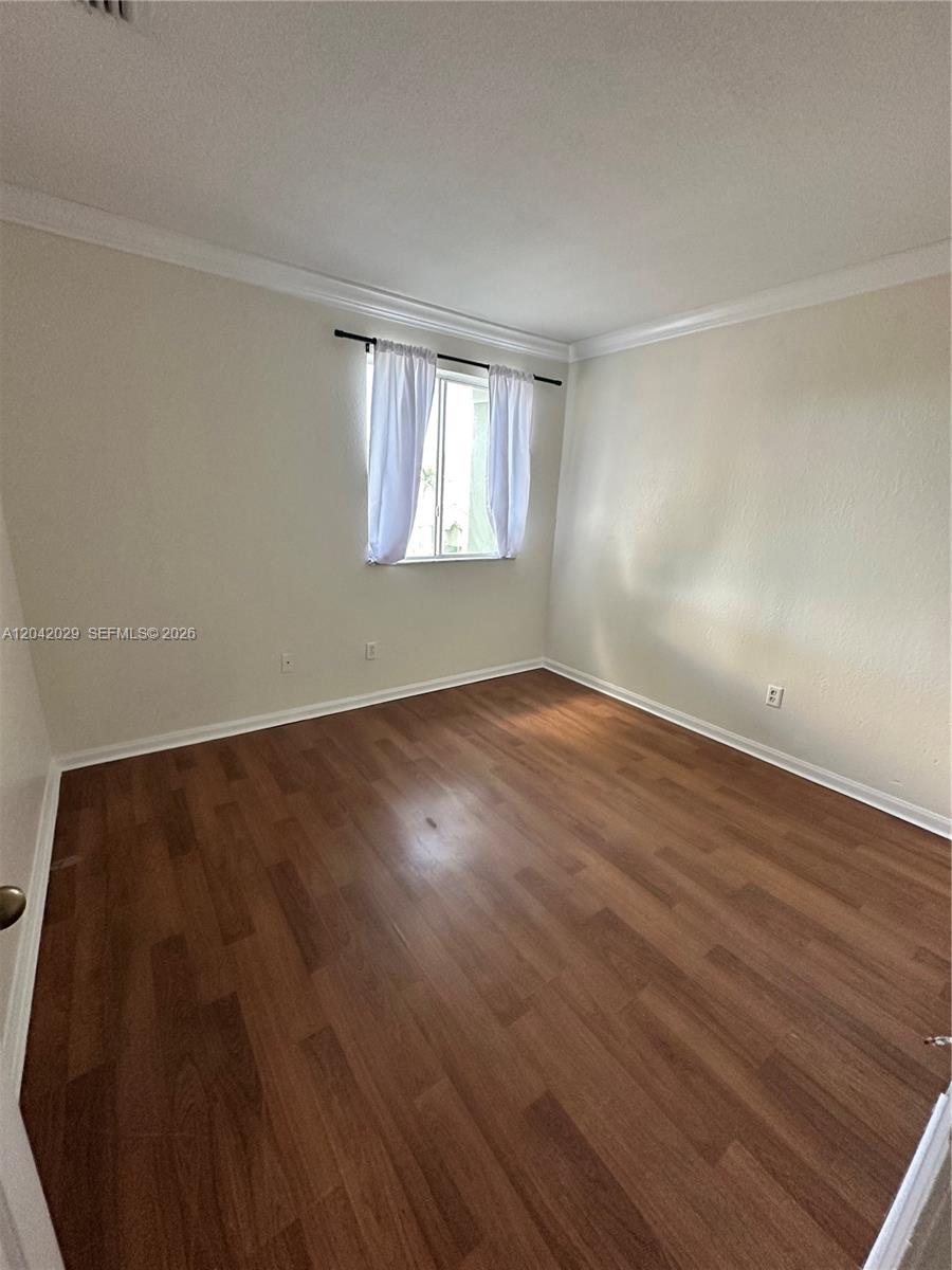 An empty bedroom features light-colored walls, white trim, and wood-look laminate flooring — 2704 SE 15th Pl, Homestead FL 33035, HOMESTEAD, FL