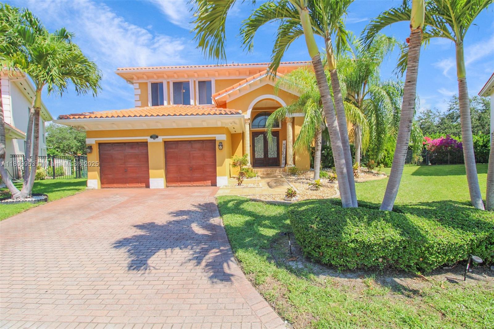 A two-story yellow house features a tiled roof, a two-car garage, and palm trees — 7753 SW 193rd St, Cutler Bay FL 33157, CUTLER BAY, FL