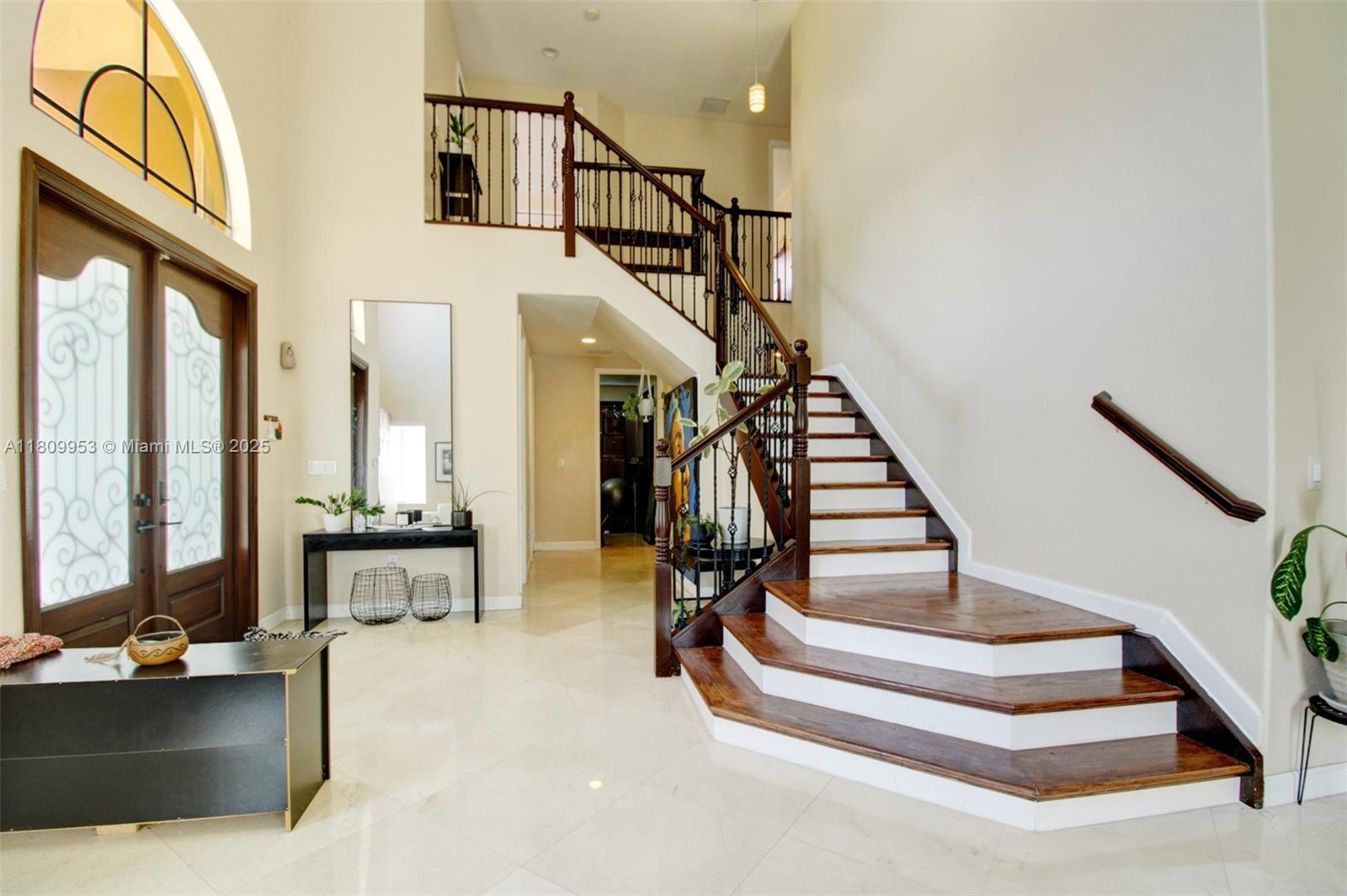 A bright foyer features a grand staircase with dark wood treads and a wrought iron railing — 7753 SW 193rd St, Cutler Bay FL 33157, CUTLER BAY, FL