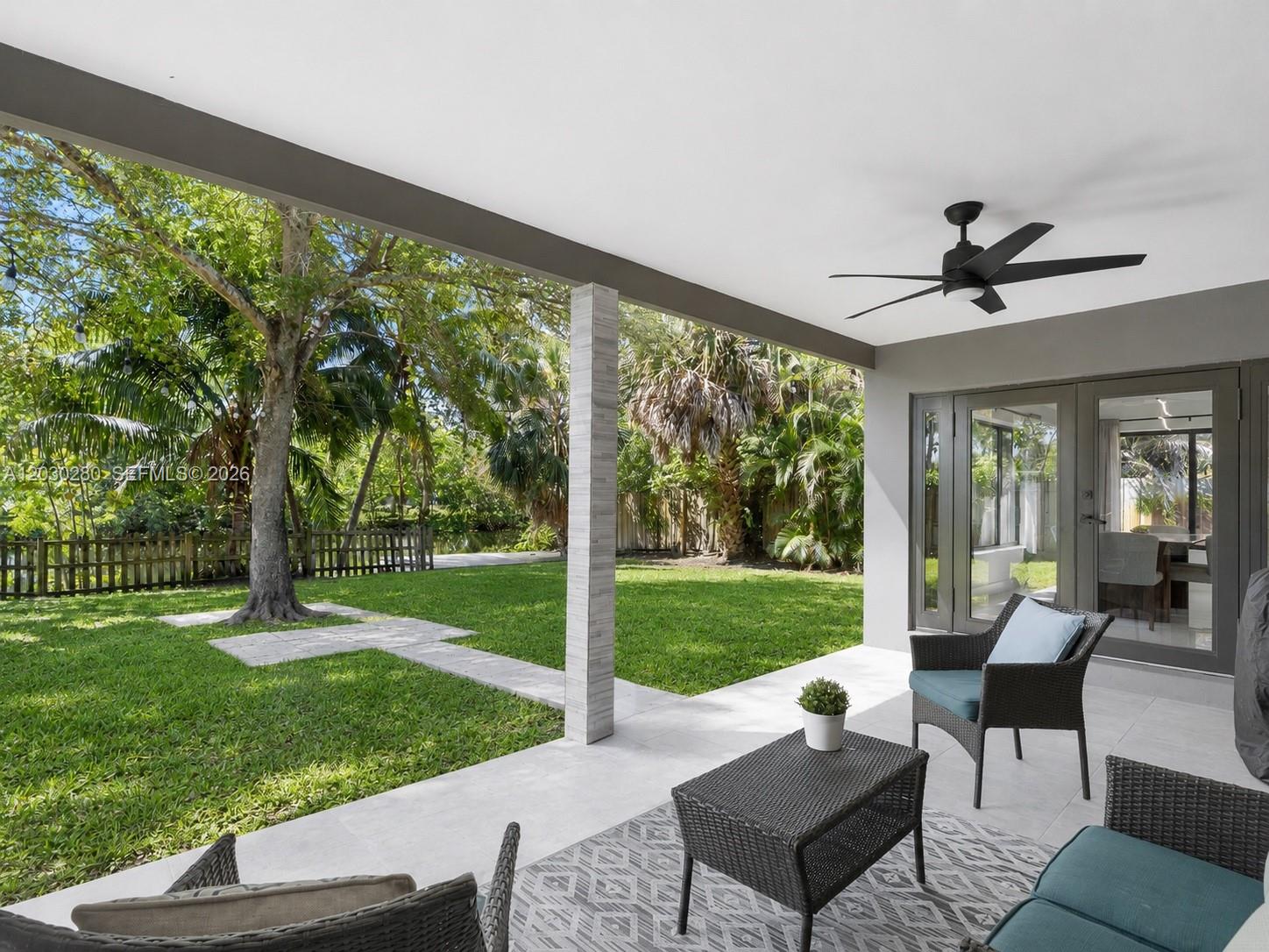 A covered patio features tiled flooring, outdoor furniture, a ceiling fan, and a grassy backyard — 400 NW 30th Ct, Wilton Manors FL 33311, WILTON MANORS, FL