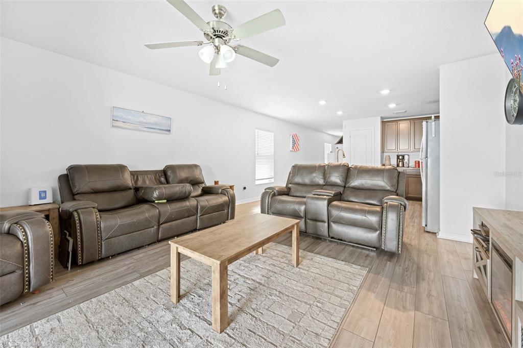 A living room features gray reclining sofas, a wooden coffee table, and light wood flooring — 30067 FEDORA CIRCLE, BROOKSVILLE, FL