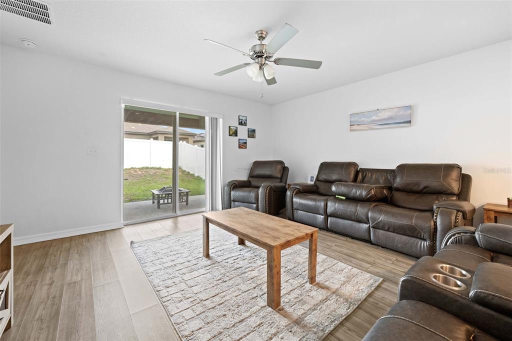 A living room features brown leather furniture, a wooden coffee table, and a sliding glass door — 30067 FEDORA CIRCLE, BROOKSVILLE, FL