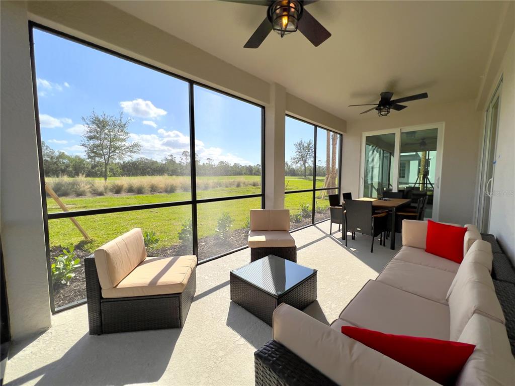 A screened-in patio features outdoor furniture, ceiling fans, and views of a grassy field — 14656 SYCAMORE COURT UNIT 3211, PUNTA GORDA, FL