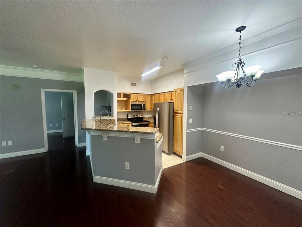 An open-concept living area features dark hardwood floors, grey walls, and a kitchen with cabinetry — 3446 SOHO STREET UNIT 104, ORLANDO, FL
