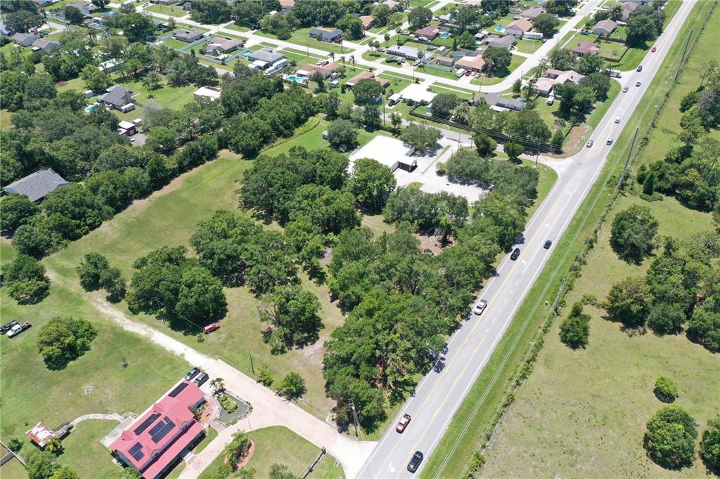 An aerial view shows a large, tree-filled lot with a building and a nearby house — 2351 CANOE CREEK ROAD, ST CLOUD, FL