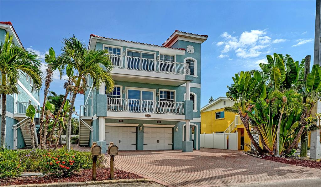 A three-story blue house with a two-car garage and balconies sits on a paved driveway — 2317 AVENUE C UNIT 300, BRADENTON BEACH, FL