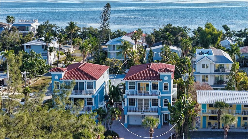 An aerial view shows a blue three-story house with a red tile roof near water — 2317 AVENUE C UNIT 300, BRADENTON BEACH, FL