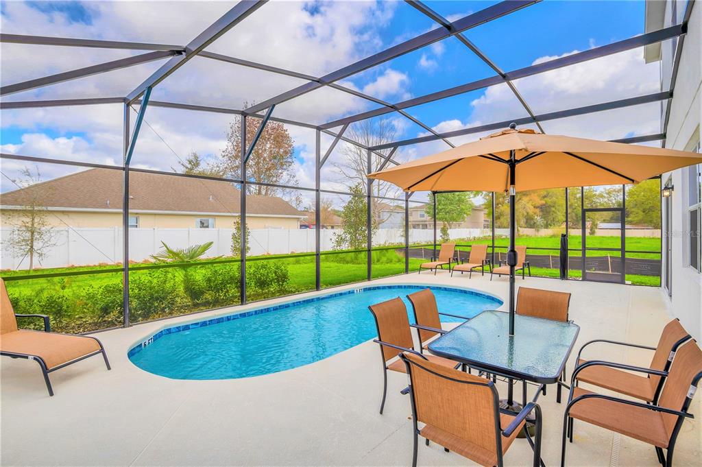 A screened-in patio features a swimming pool, outdoor dining set, and lounge chairs — 4481 MONADO DRIVE, KISSIMMEE, FL