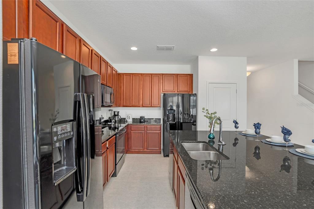 A kitchen features dark wood cabinets, black appliances, granite countertops, and a large island — 4481 MONADO DRIVE, KISSIMMEE, FL