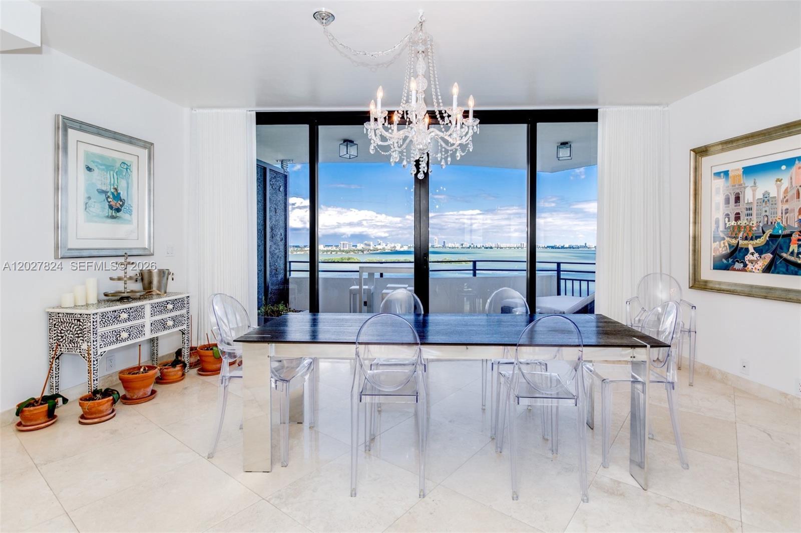 A dining room features a dark table, clear chairs, a crystal chandelier, and balcony views — 720 NE 69th St # 19S, Miami FL 33138, MIAMI, FL