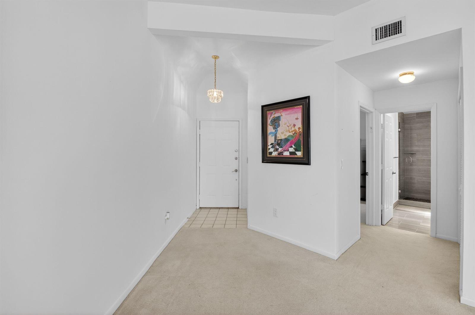 A carpeted entryway features a white front door, a hanging light fixture, and wall art — 7460 La Paz Boulevard # 306, Boca Raton FL 33433, BOCA RATON, FL