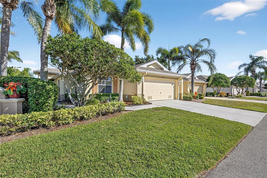 A single-story house with a beige exterior, a two-car garage, and palm trees in front — 1201 CORINTH GREENS DRIVE UNIT 58, SUN CITY CENTER, FL