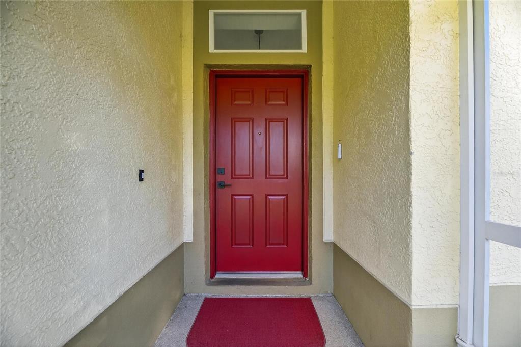 A red front door with a transom window sits in a recessed entryway — 1201 CORINTH GREENS DRIVE UNIT 58, SUN CITY CENTER, FL