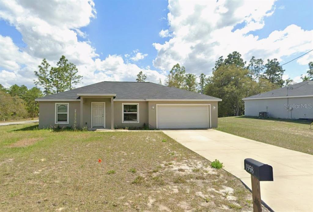 A single-story house with a beige exterior, a two-car garage, and a concrete driveway — 1958 W LINDEN DRIVE, CITRUS SPRINGS, FL