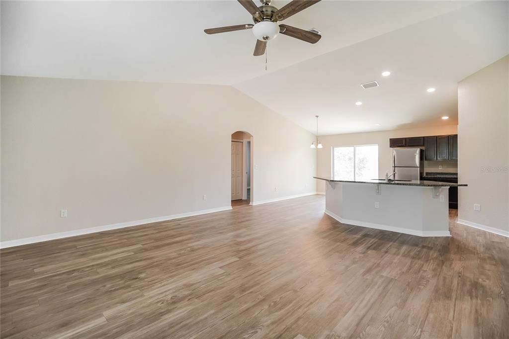 An open-concept living area features wood-look flooring, a vaulted ceiling, and a kitchen island — 1958 W LINDEN DRIVE, CITRUS SPRINGS, FL