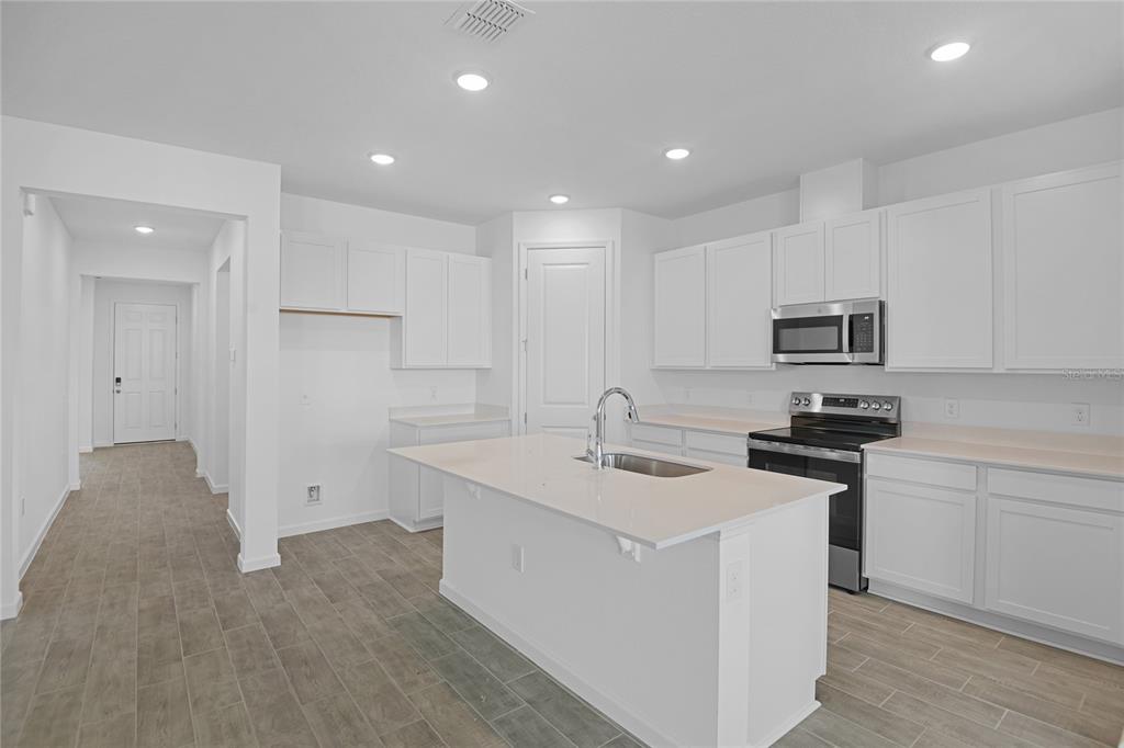 A modern kitchen features white cabinets, a central island with a sink, and tile flooring — 5351 MICKEY AVENUE, WINTER HAVEN, FL