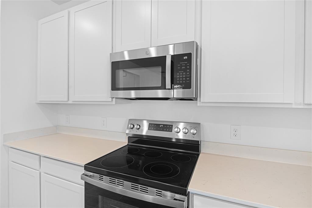 A kitchen features white cabinets, a stainless steel microwave, and a black electric range — 5351 MICKEY AVENUE, WINTER HAVEN, FL