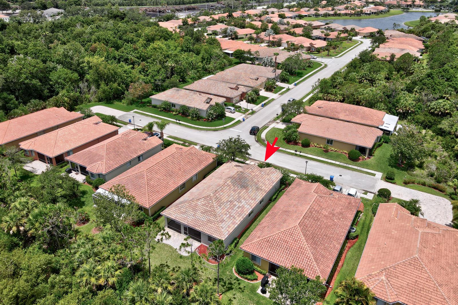 An aerial view shows a suburban neighborhood with tile-roofed houses and a red arrow pointing down — 6188 Dorchester Way, Vero Beach FL 32966, VERO BEACH, FL