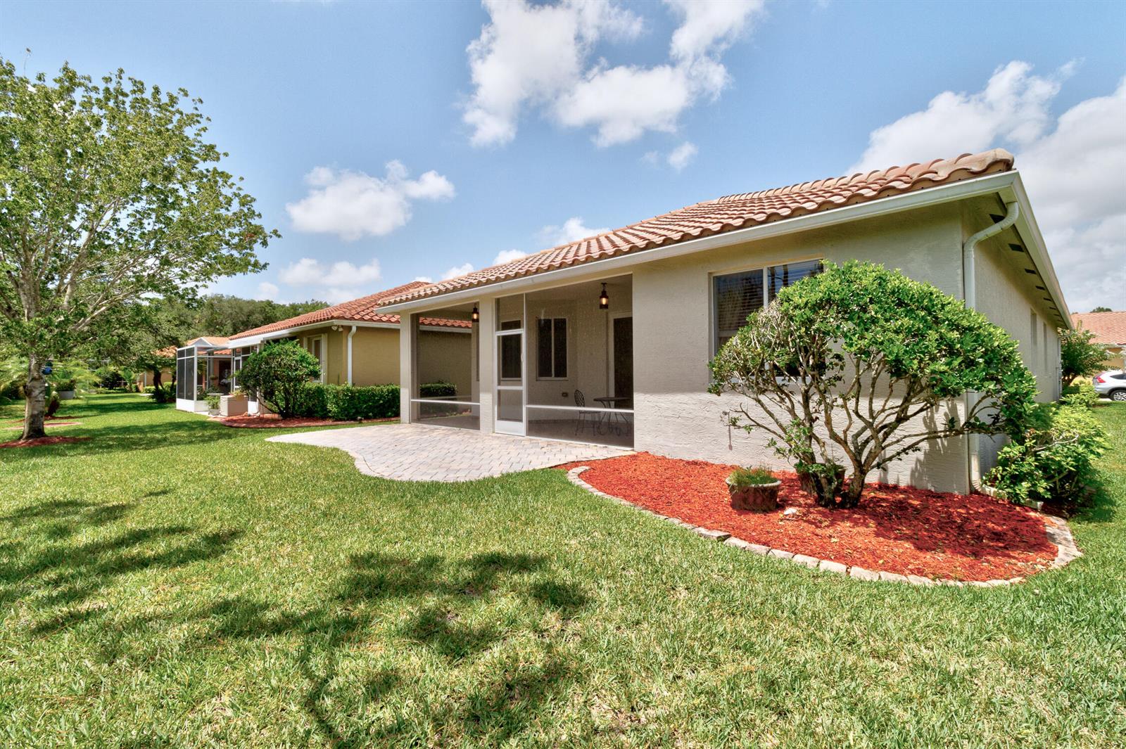 A house exterior features a screened-in patio, a paver walkway, and a landscaped garden bed — 6188 Dorchester Way, Vero Beach FL 32966, VERO BEACH, FL