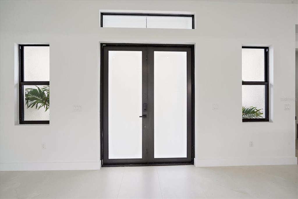 A modern entryway features double glass doors flanked by two narrow windows and a transom — 17328 ORION AVENUE, PORT CHARLOTTE, FL