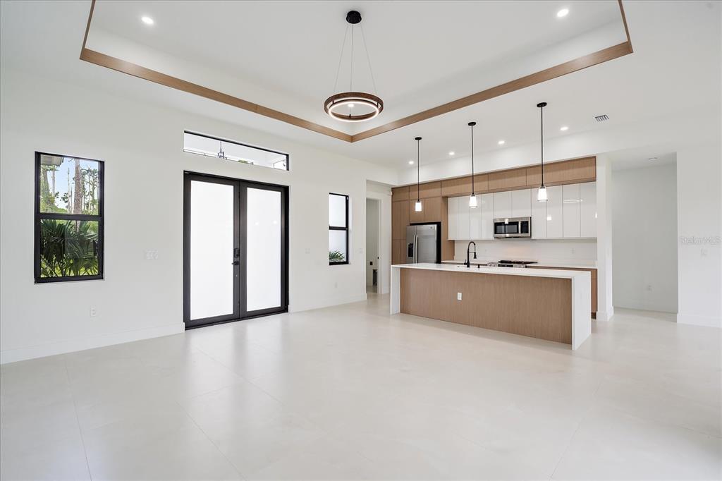 A modern open-concept kitchen and living area features white walls, light tile floors, and wood accents — 17328 ORION AVENUE, PORT CHARLOTTE, FL