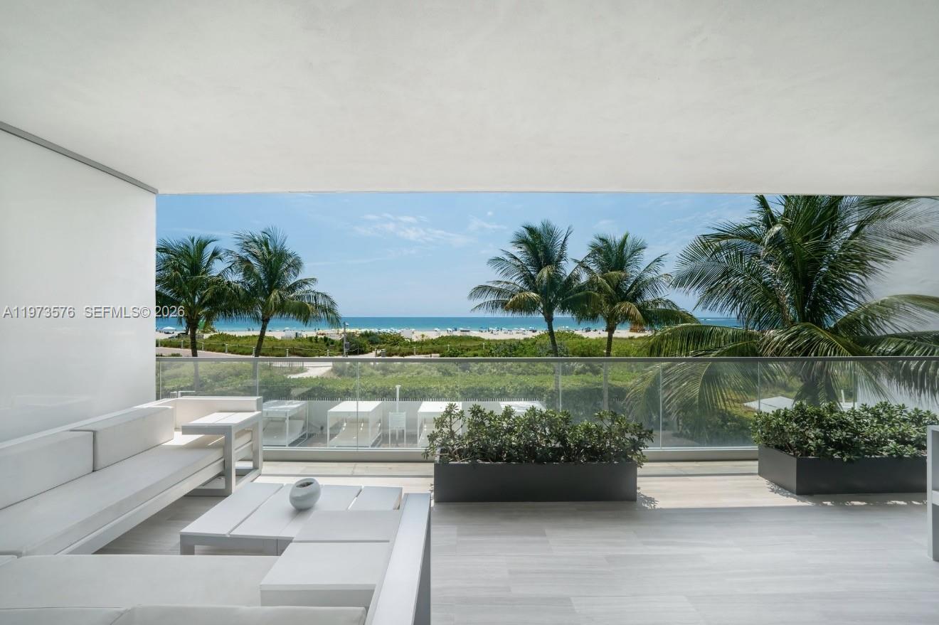 A modern balcony features white furniture, planters, and a glass railing overlooking the beach — 321 Ocean Dr # 200, Miami Beach FL 33139, MIAMI BEACH, FL