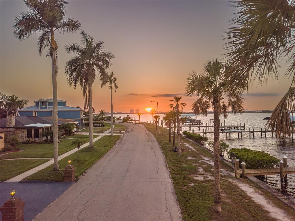 A paved road runs between waterfront homes and a dock at sunset — 2410 RIVERSIDE DRIVE E, BRADENTON, FL