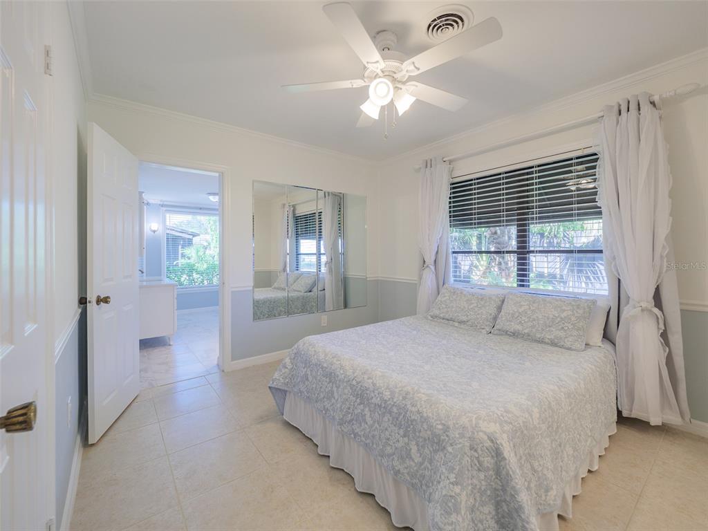A bedroom features tile flooring, a ceiling fan, a mirrored wall, and a queen bed — 2410 RIVERSIDE DRIVE E, BRADENTON, FL