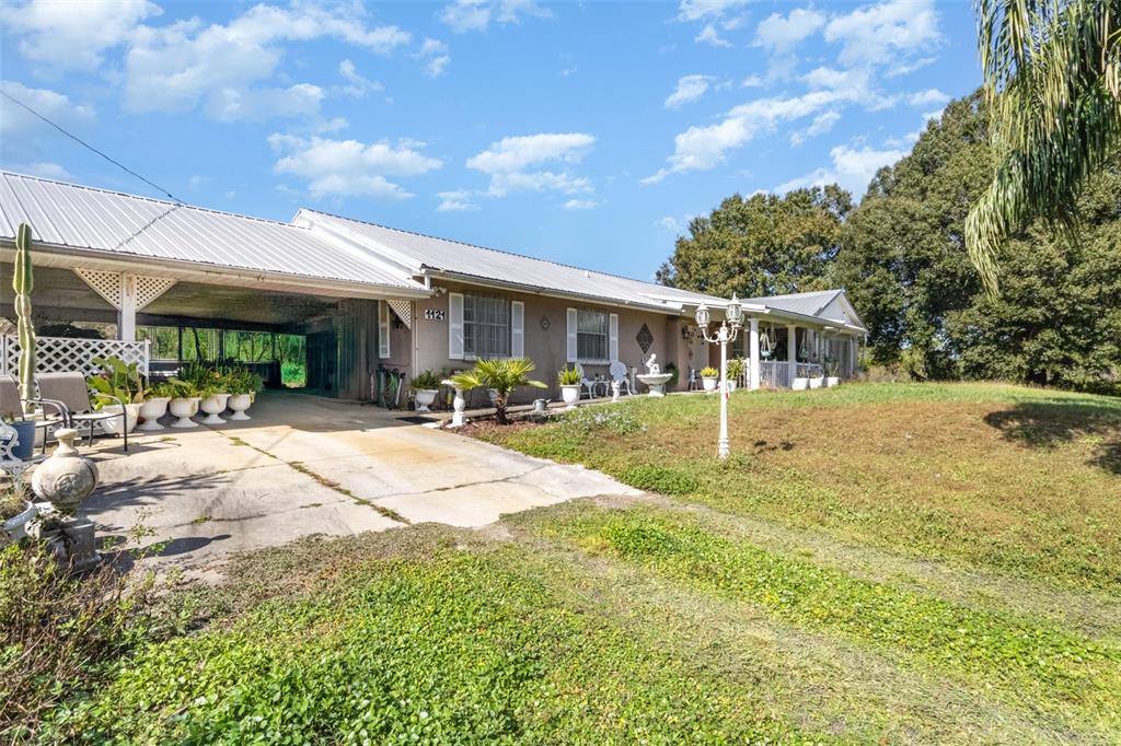 A single-story house with a metal roof, a carport, and a grassy front yard — 1121 CLARK BAY ROAD, DELAND, FL
