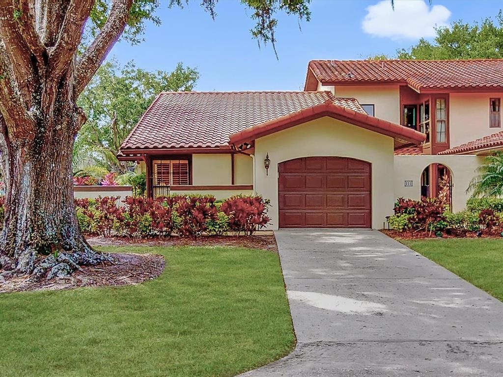 A single-story house with a brown tile roof, a garage, and a large tree in front — 112 COVENTRY LANE, HAINES CITY, FL