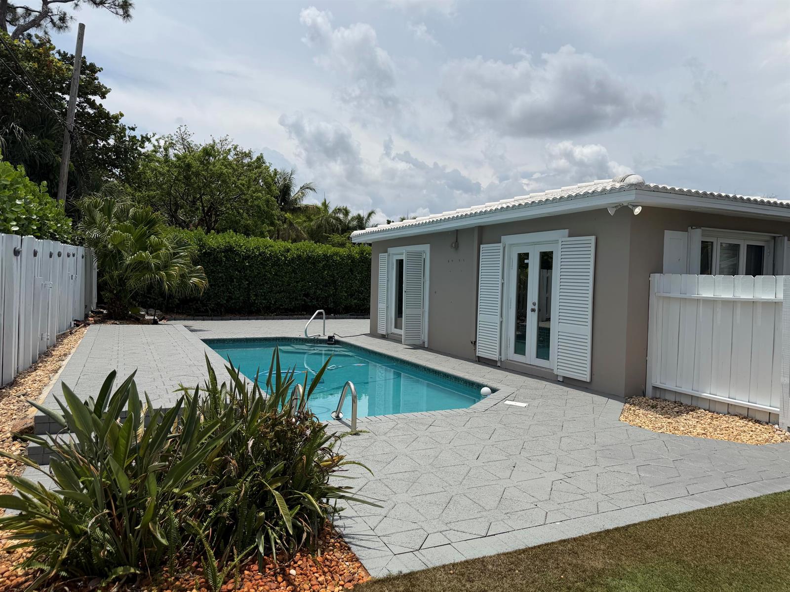A backyard features a rectangular swimming pool surrounded by a gray patterned concrete patio — 204 S Seacrest Circle, Delray Beach FL 33444, DELRAY BEACH, FL
