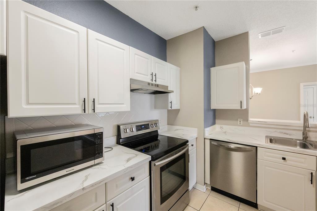 A kitchen features white cabinets, stainless steel appliances, and white marble-look countertops — 18001 RICHMOND PLACE DRIVE UNIT 1010, TAMPA, FL