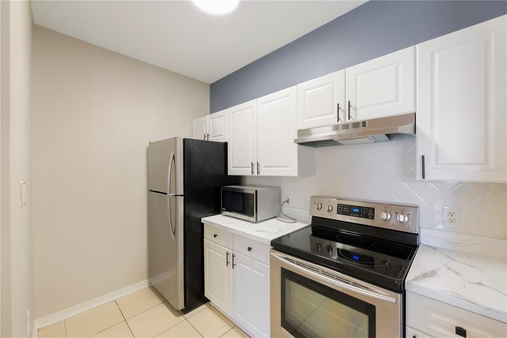 A kitchen features white cabinets, stainless steel appliances, and light-colored countertops — 18001 RICHMOND PLACE DRIVE UNIT 1010, TAMPA, FL