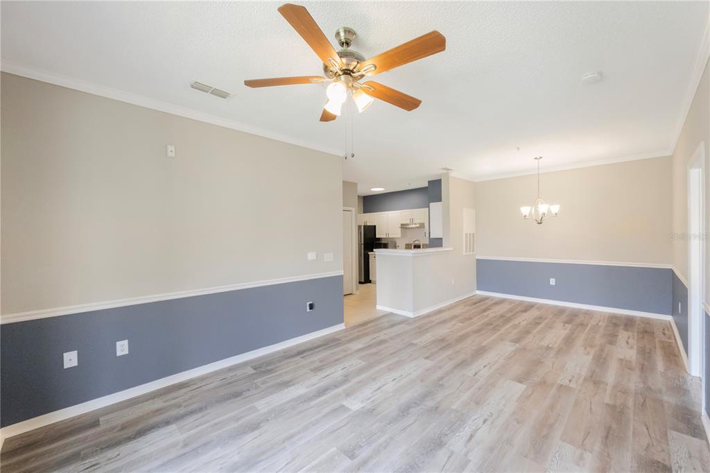 An open-concept living and dining area features two-tone walls, wood-look flooring, and a ceiling fan — 18001 RICHMOND PLACE DRIVE UNIT 1010, TAMPA, FL