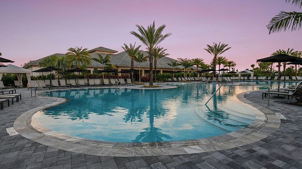 An outdoor swimming pool with lounge chairs and palm trees sits before a large building — 4451 OCHOS RIOS PLACE, KISSIMMEE, FL