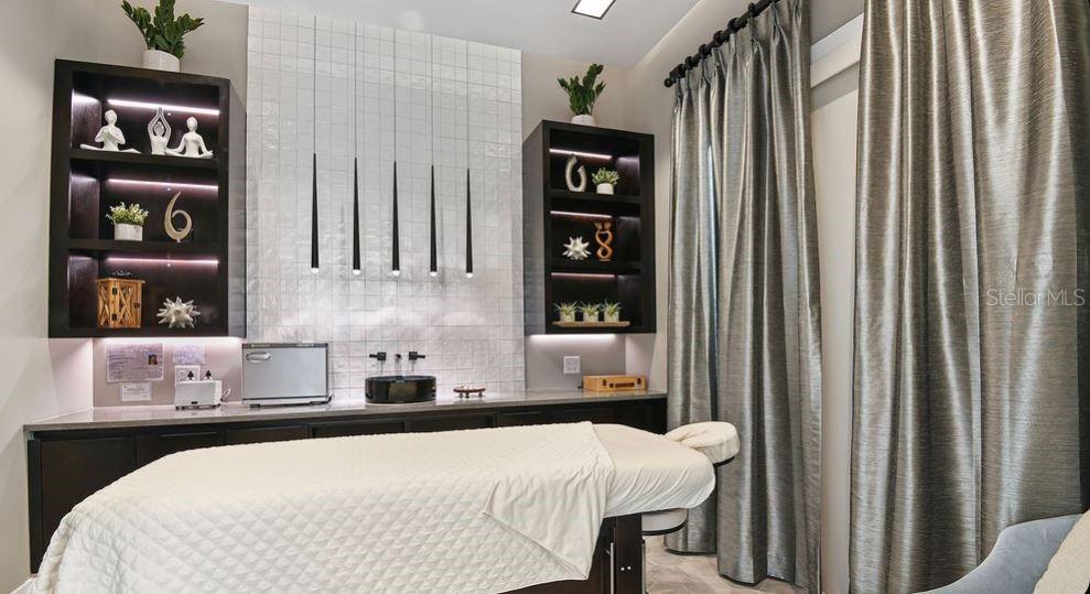 A spa treatment room features a massage table, dark cabinetry, and a tiled accent wall — 4451 OCHOS RIOS PLACE, KISSIMMEE, FL