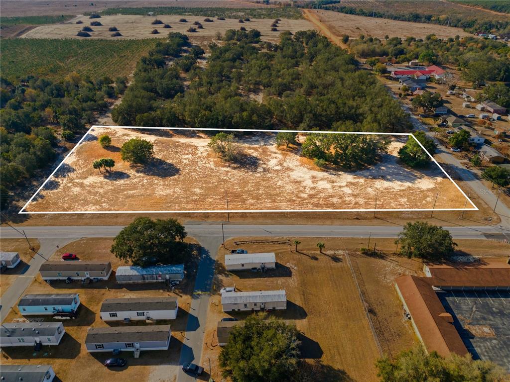 An aerial view shows a rectangular, cleared vacant lot bordered by a road and trees — FRIEDLANDER ROAD, LAKE WALES, FL